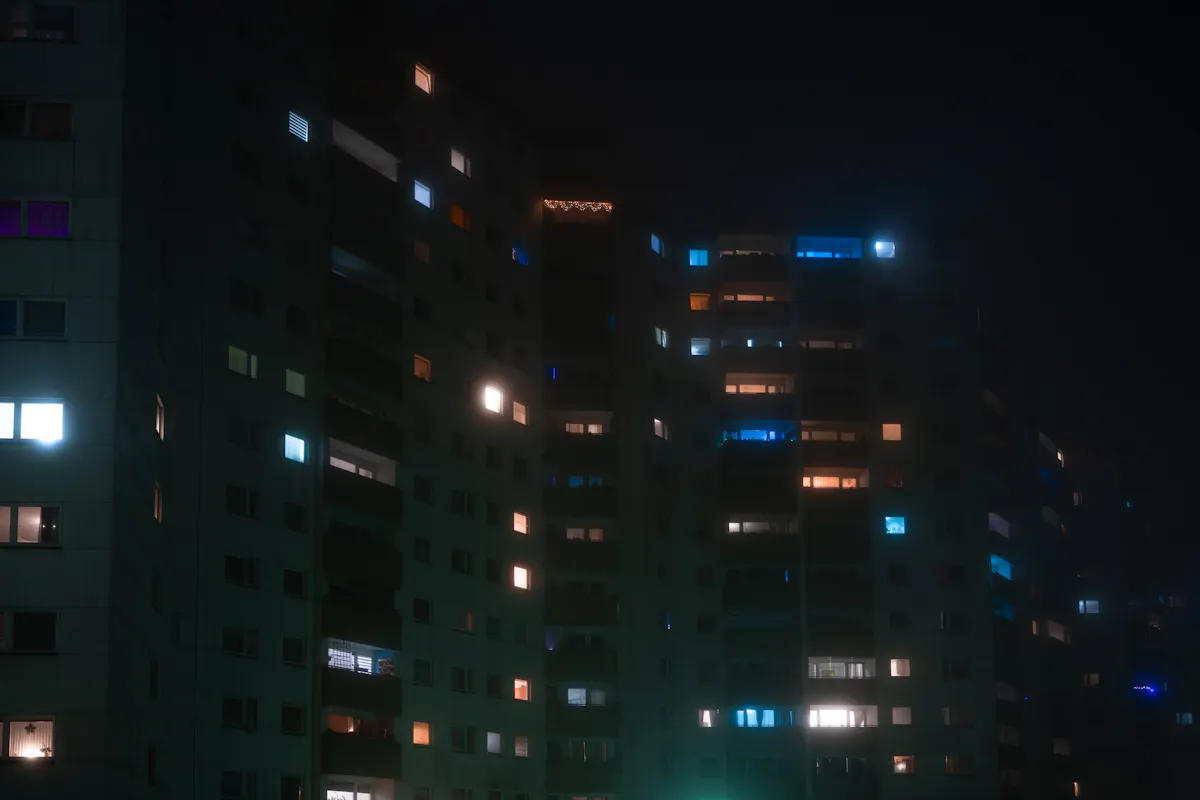 Apartment building at night with many windows lit from occupied units