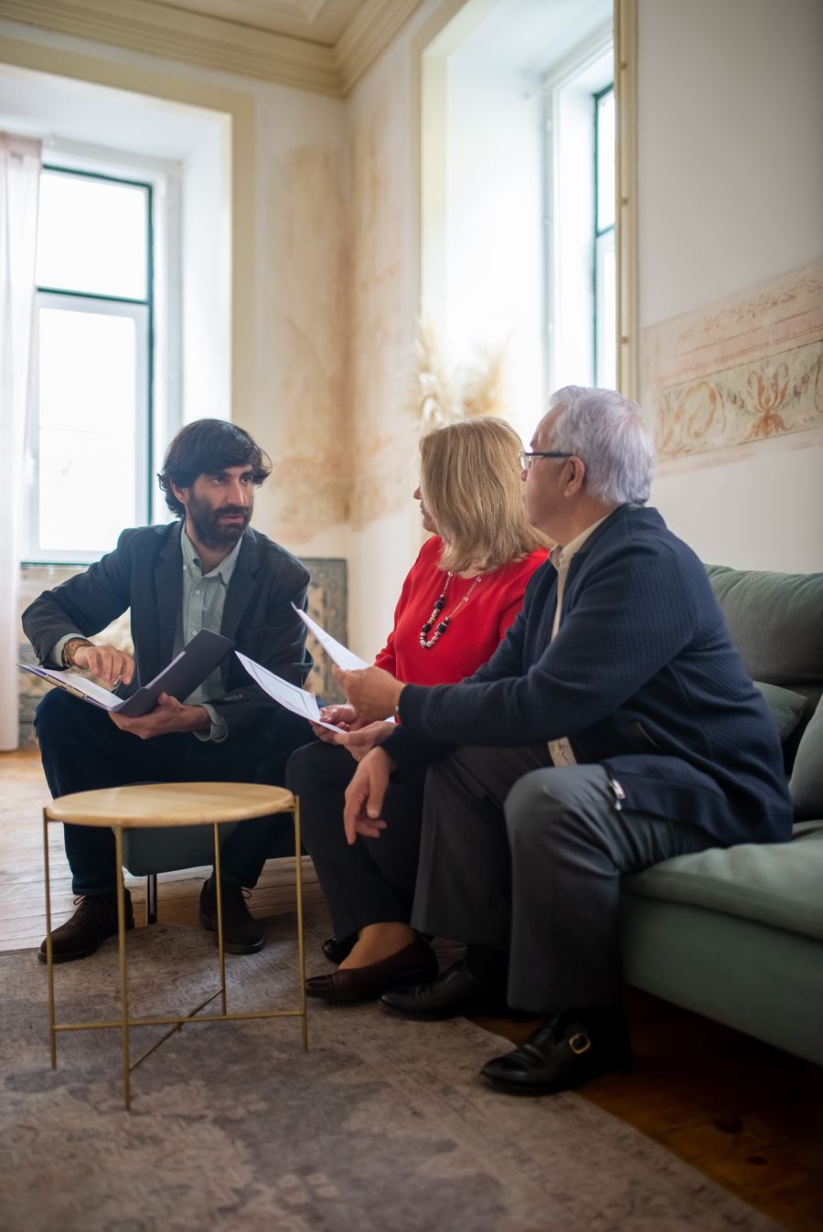 An adviser and a couple reviewing project documents together in a warm, relaxed setting