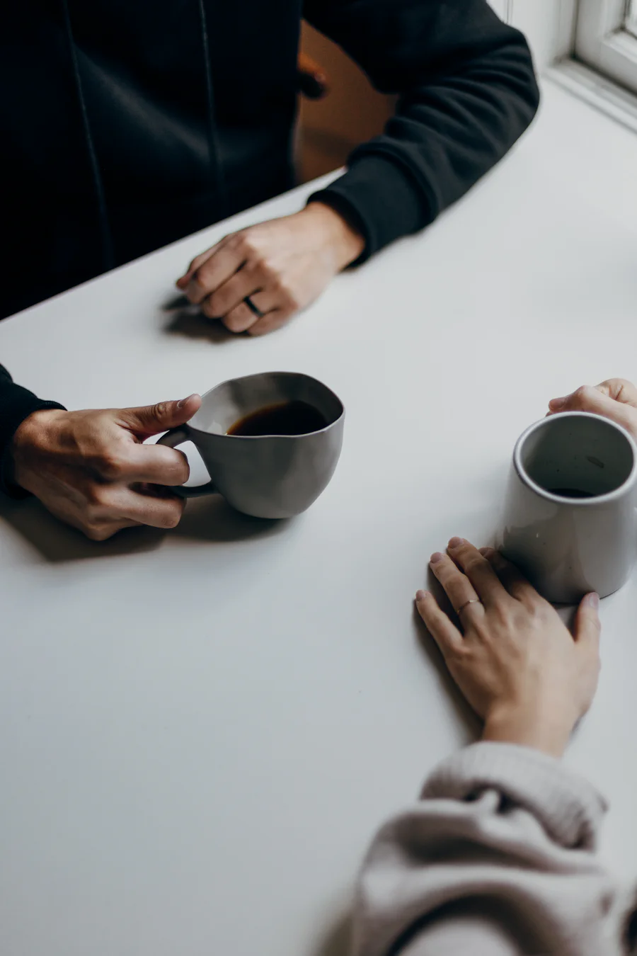 Two people in a relaxed conversation over coffee at a table
