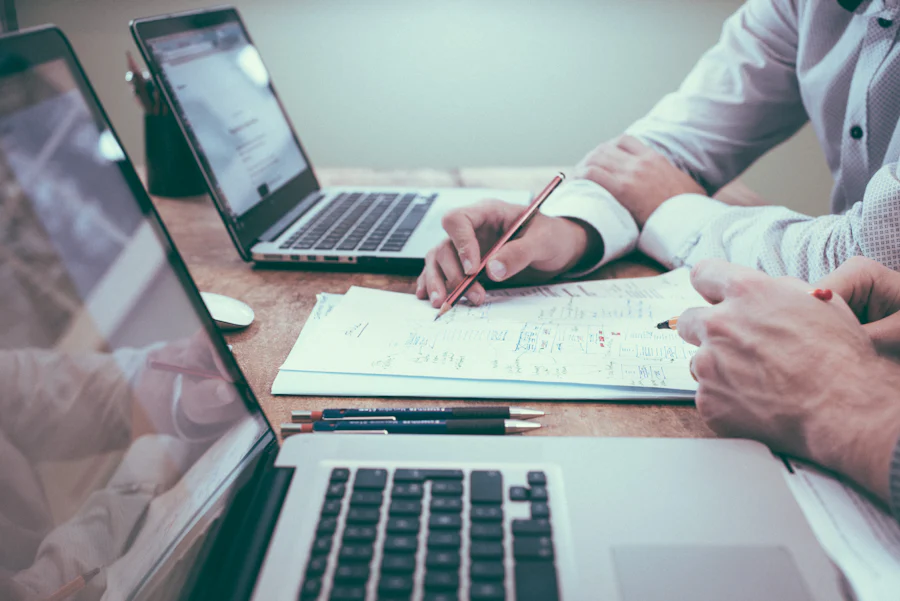 Two people reviewing investment figures over documents and laptops